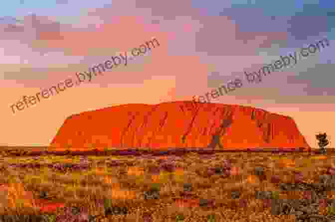 Stunning Sunset Over The Sacred Monolith Of Uluru (Ayers Rock),Casting A Warm Glow On The Surrounding Desert Landscape The Jacaranda Trail: A Journey Of Discovery Down Under (Travels Down Under 1)